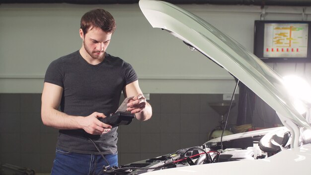 car-mechanic-using-electrical-tool-testing-car-system-garage-repair_186451-622